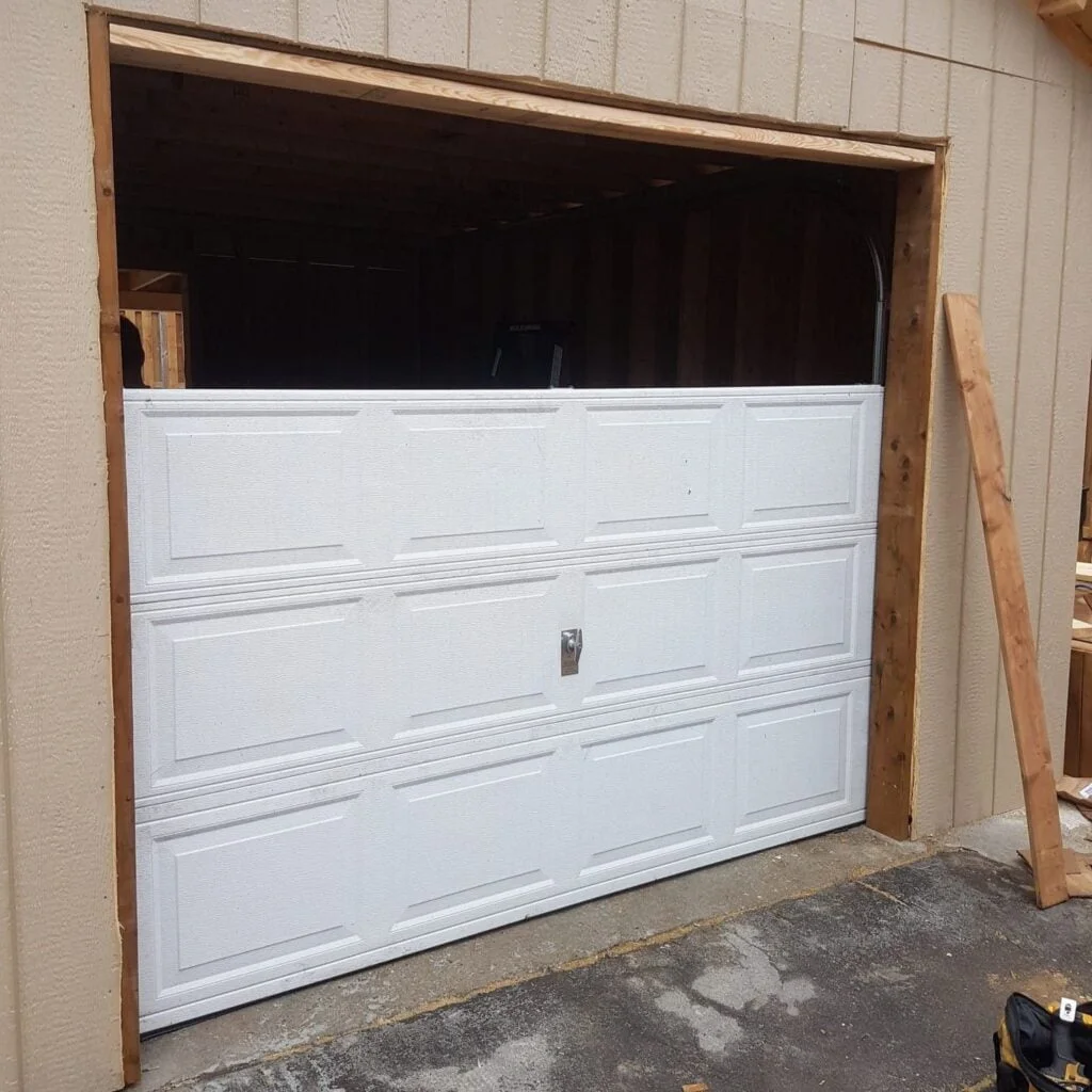 Technician replacing a damaged garage door panel in Westwood.